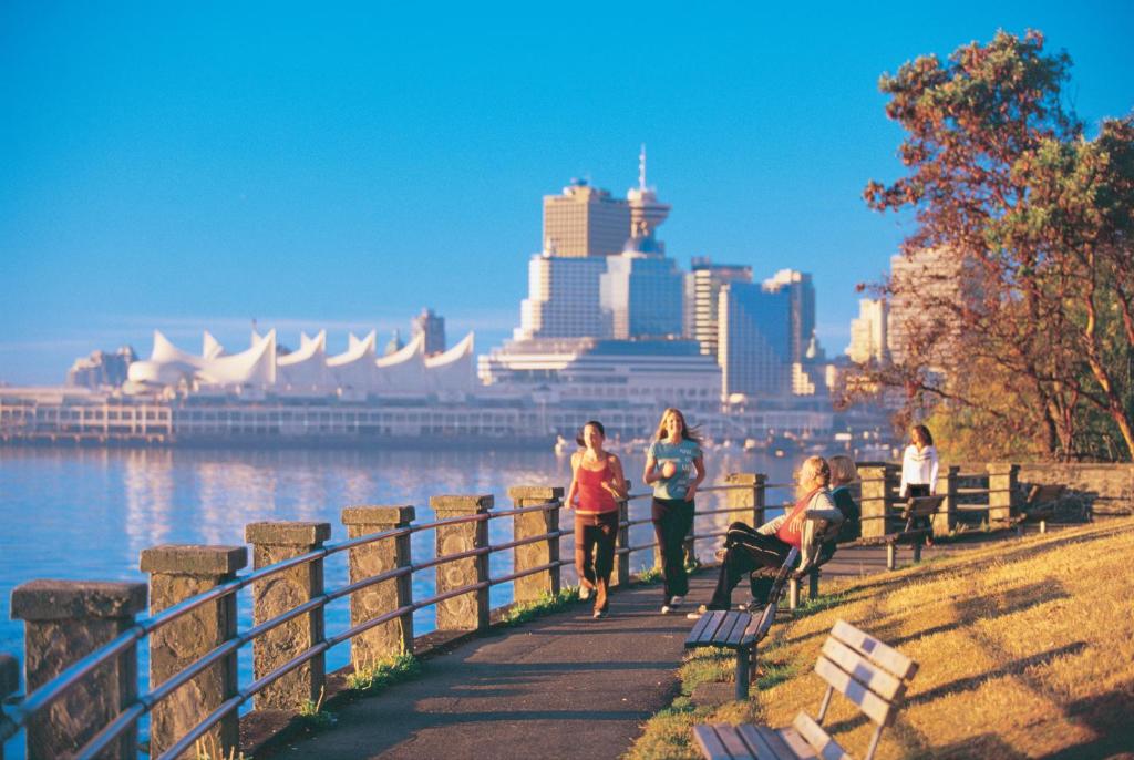 A Filipino traveler strolls through Vancouver’s Stanley Park, with lush greenery and the city skyline in the distance