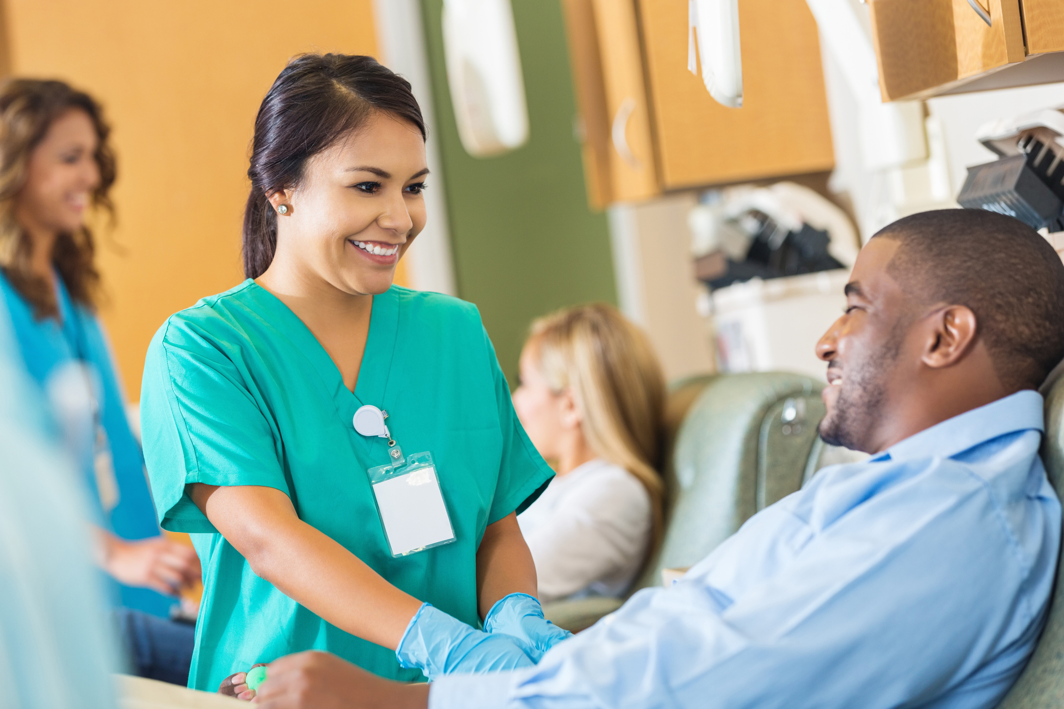 : A nurse from an international background, in a mental health nurse uniform, engages with a patient in a calm, supportive setting