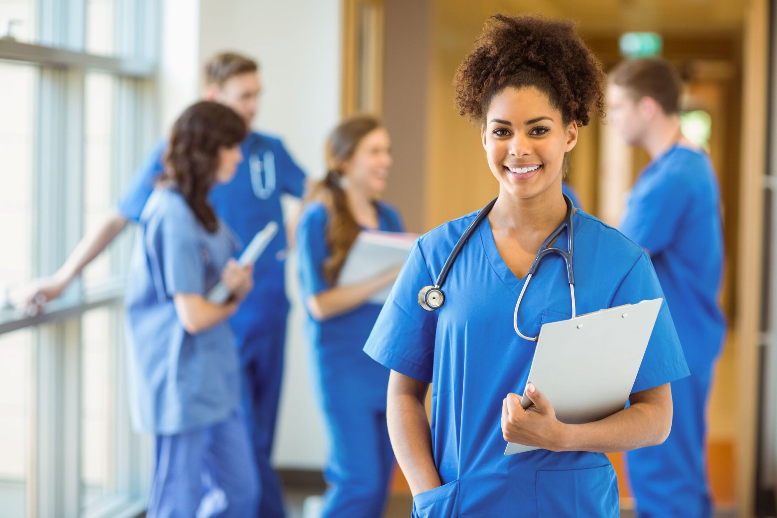 A nurse from an international background, in scrubs, checks a patient’s chart in a modern regional hospital in Victoria