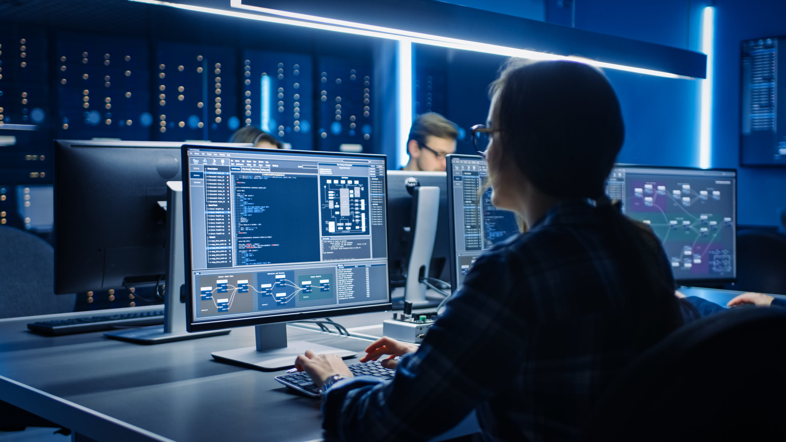 A software engineer from an international background, working at a laptop in a modern Berlin tech office with collaborative team members in the background